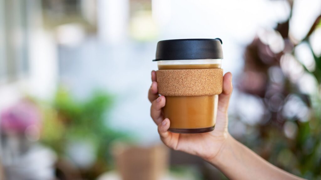 Mano aguantando una taza de café reutilizable.