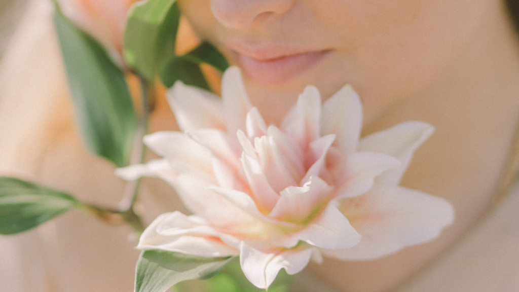 Mujer oliendo una hermosa flor para aumentar su energía y positividad en verano.