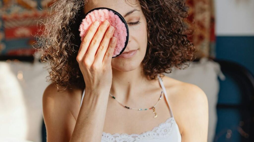 Mujer desmaquillándose con un disco de tela.