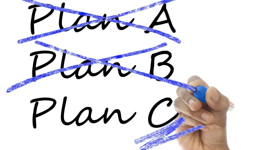 Mano tachando las palabras Plan A y Plan B, quedándose con el Plan C  sin tachar