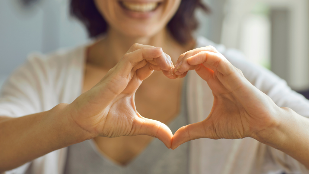 Mujer haciendo la forma de un corazón con las manos.