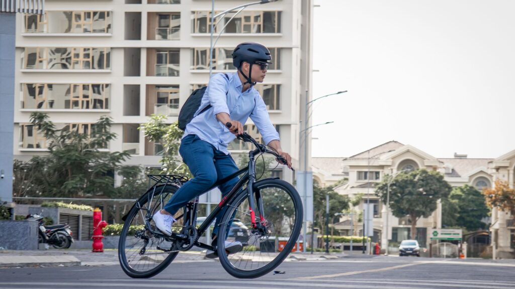 Una persona monta en bicicleta por una calle. Al fondo, se ven edificios y un cielo despejado.